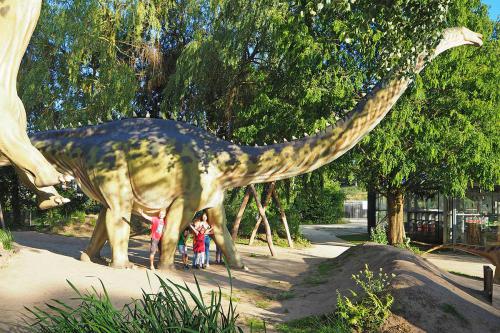 Gezin staat tussen de poten van een levensgrote Diplodocus in Dinoland Zwolle